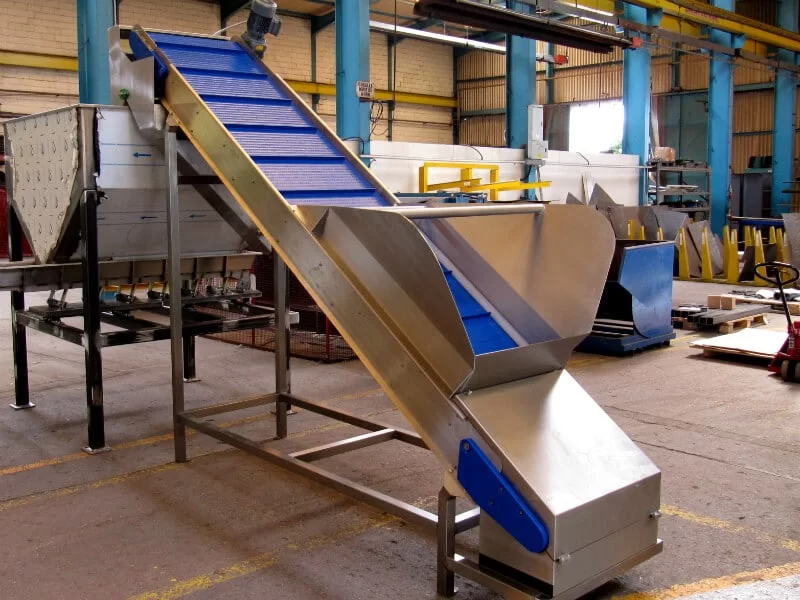 Inclined belt conveyor feeding a hopper.