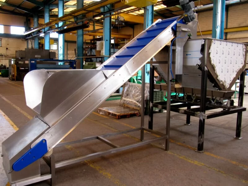 Inclined belt conveyor feeding a hopper.