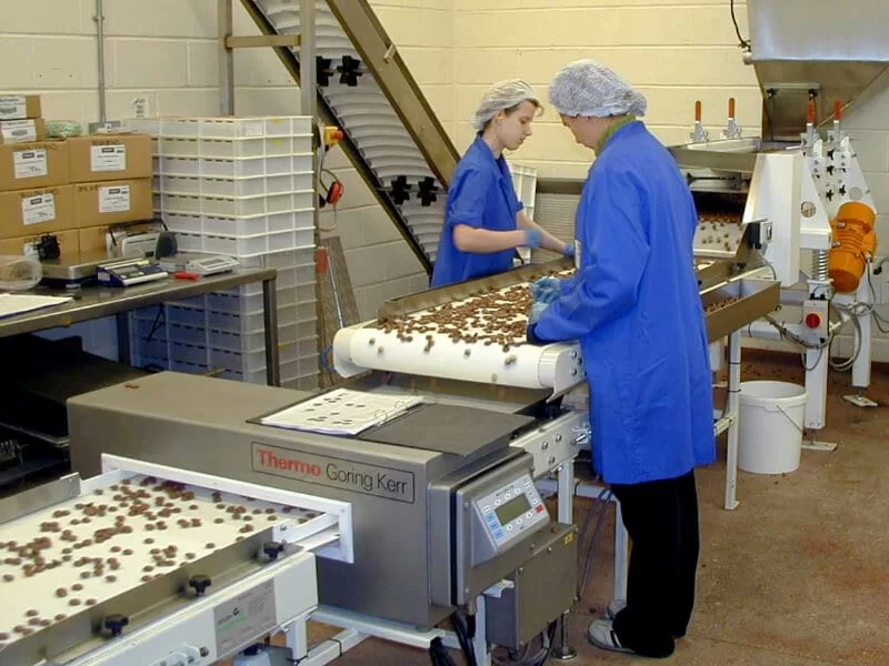 Belt conveyor and metal detector handling chocolate hoops.